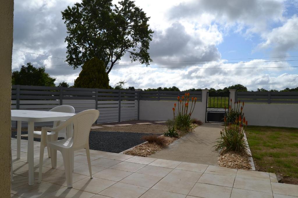 eine Terrasse mit einem Tisch, Stühlen und einem Zaun in der Unterkunft chez juliette in Mauléon