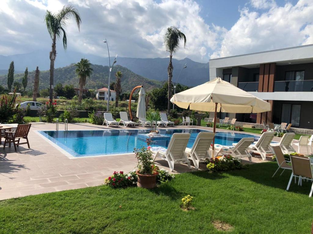 een zwembad met stoelen en een parasol naast een gebouw bij Mandalina Apartments in Ağva