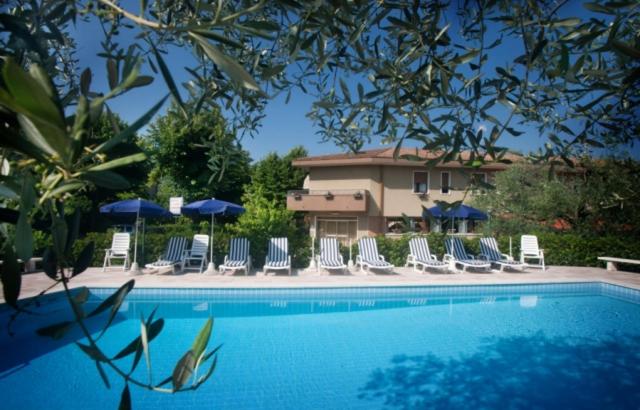 un grupo de sillas y sombrillas junto a una piscina en Hotel Lory, en Garda