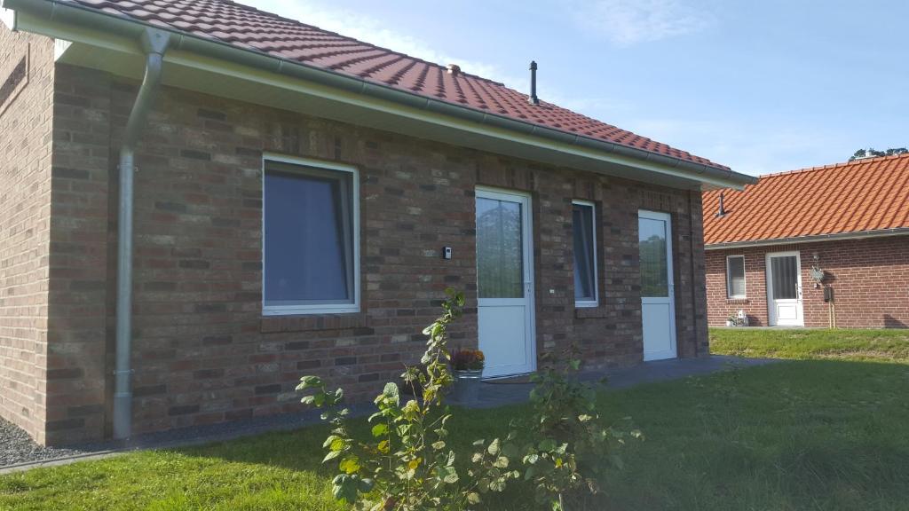 a brick house with white doors and a yard at Emsgold in Oberlangen