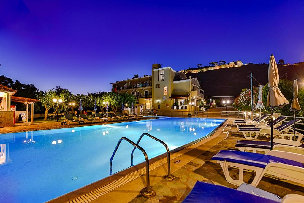 uma grande piscina com cadeiras e um edifício em Ionis Hotel em Karavádhos