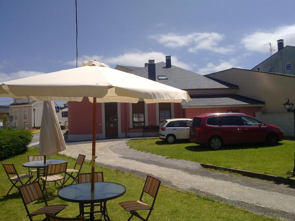 a table and chairs under an umbrella in a yard at Apartamentos Turisticos As Cetareas in Rinlo