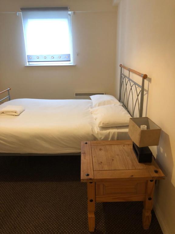 a small bedroom with a bed and a table at Wallace Hide Out in Glasgow