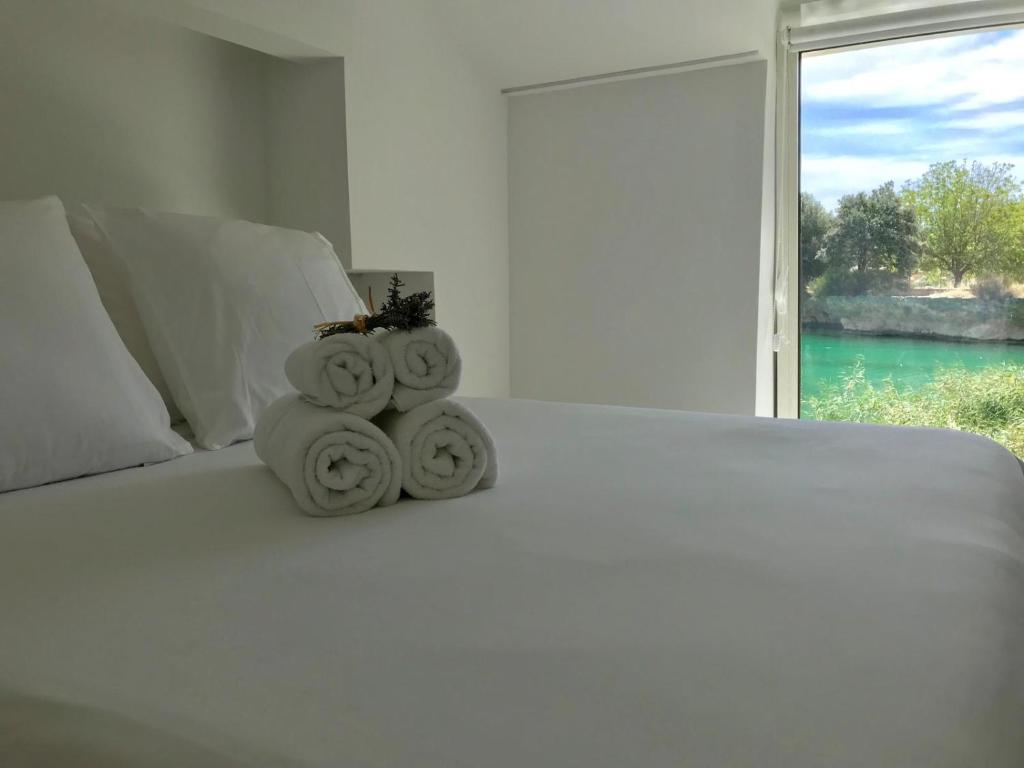 a white bed with a pile of towels on it at La Casita del Pescador in Ossa de Montiel