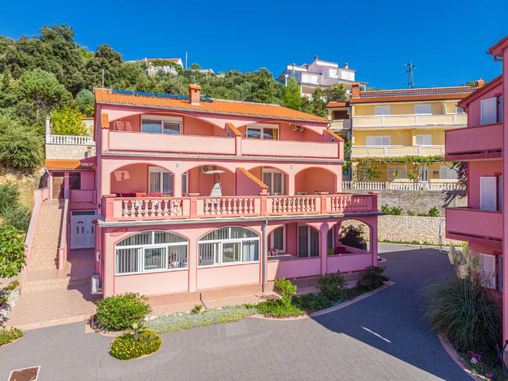una casa rosa con balcón en la parte superior en Villa Marija Apartments, en Rab