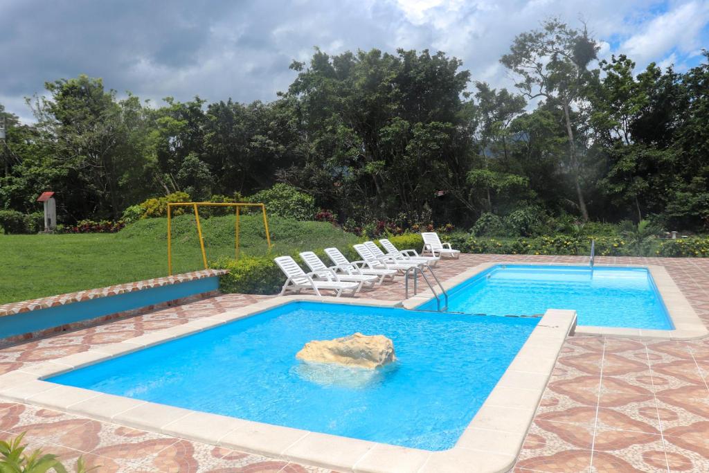 a swimming pool with chairs and a swing at Hotel Valle Verde in Valle de Anton