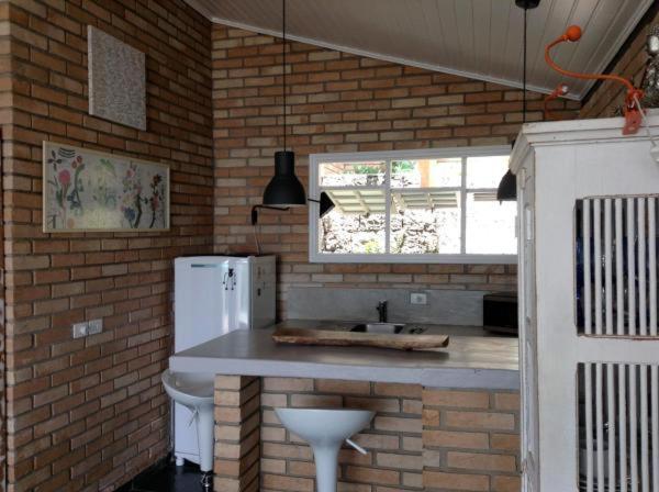 a kitchen with a white refrigerator and a brick wall at Villa Piccolo Di Mare in Ilhabela