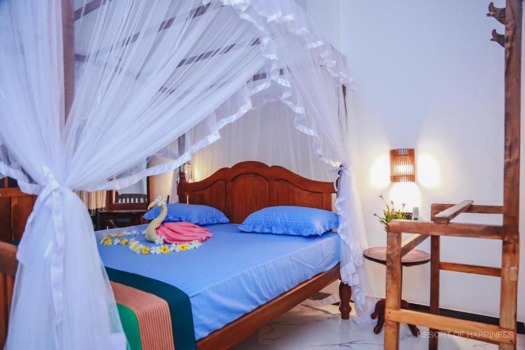 a bedroom with a canopy bed with blue pillows at Resort of Happiness in Mirissa
