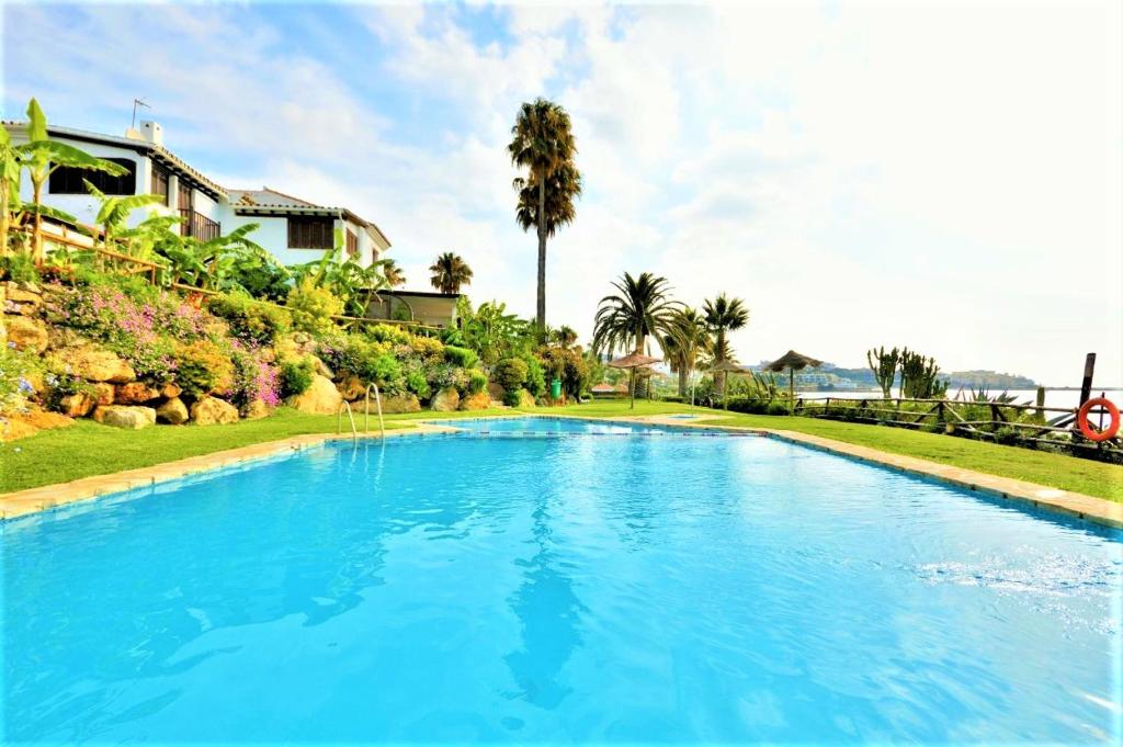 una gran piscina azul con palmeras en el fondo en VILLA BAHIA AZUL, en Estepona