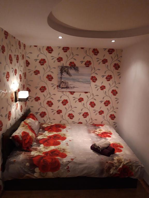 1 dormitorio con 1 cama con flores rojas en la pared en Ferry Terminal Aparts, en Klaipėda