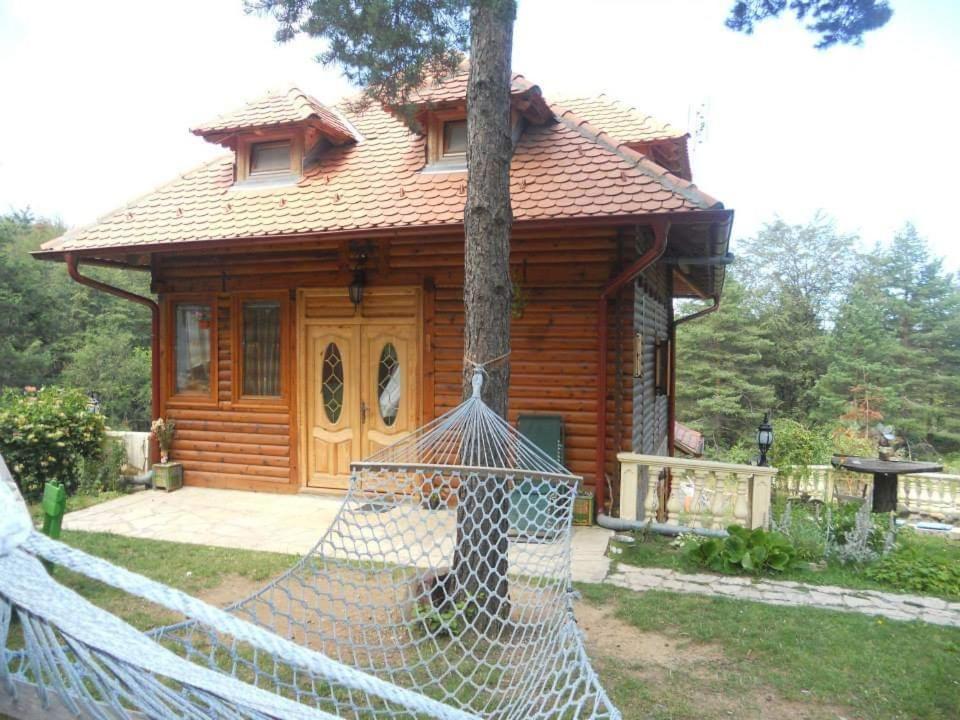 ein Blockhaus mit einer Hängematte davor in der Unterkunft Apartmani Smigic Divcibare in Divčibare