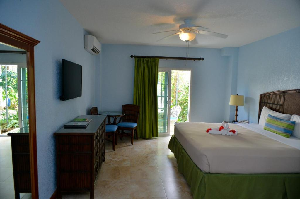 a hotel room with a bed and a desk and a table at Coco La Palm in Negril
