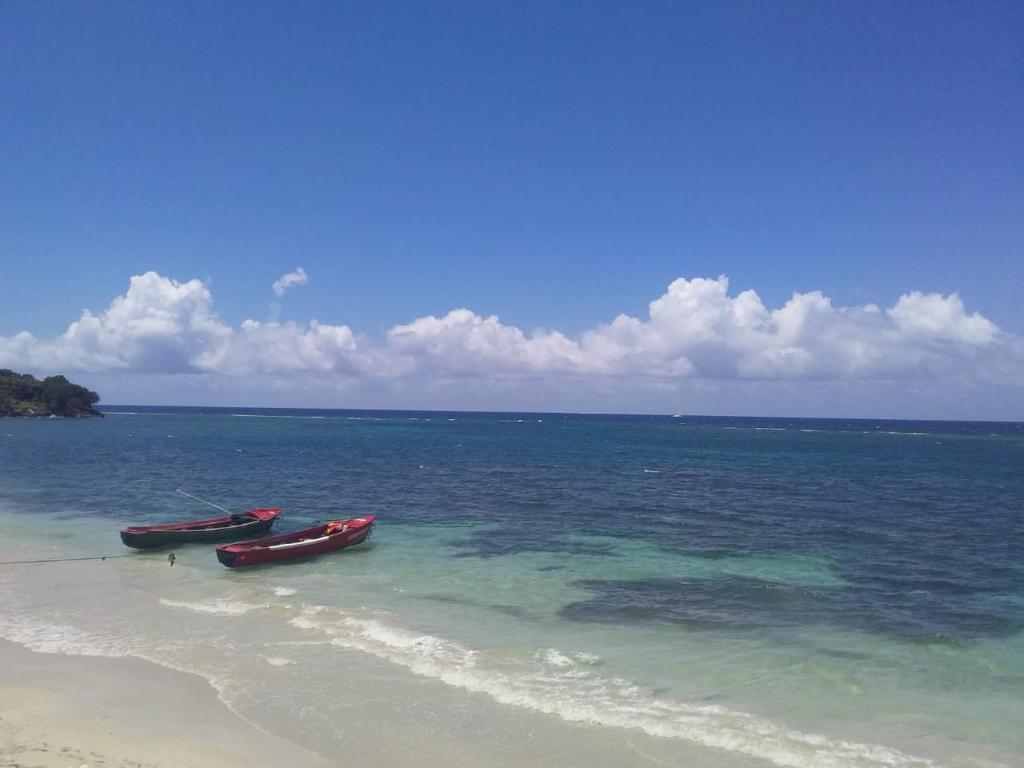 two boats sitting on a beach in the ocean at Port Antonio Brian's Beach House in Port Antonio