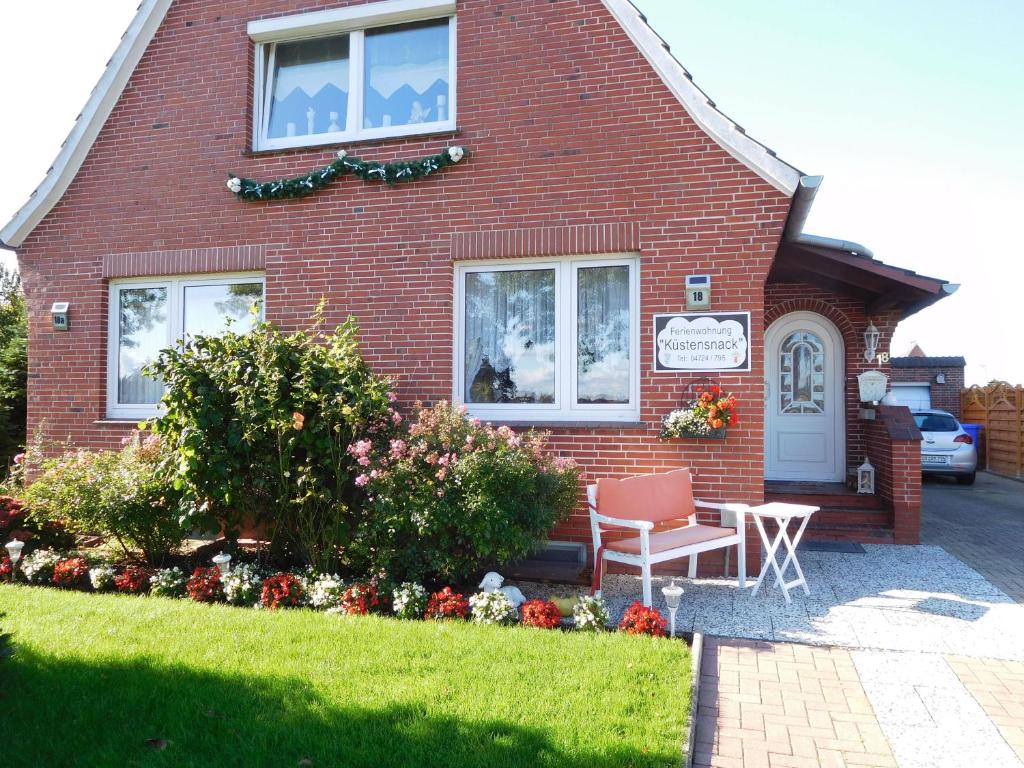 a red brick house with a chair in front of it at Ferienwohnung-Kuestensnack in Cuxhaven