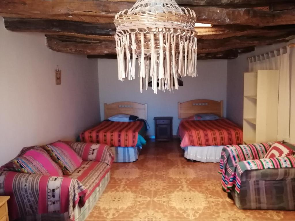 a room with three beds and a chandelier at Hostal Candelaria in San Pedro de Atacama