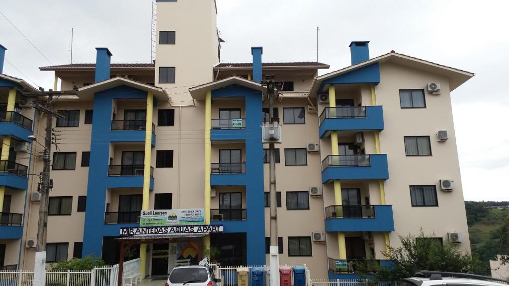 a building with blue trim and cars parked in front of it at Mirante das águas apart in Piratuba