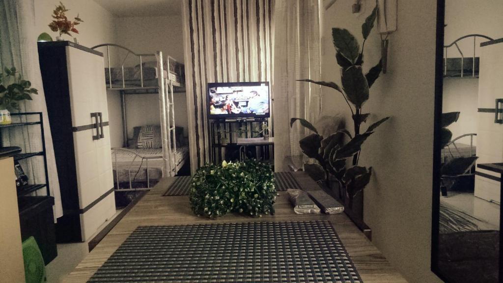 uma sala de estar com televisão e plantas em SM North FERN@GRASS RESIDENCES em Manilla