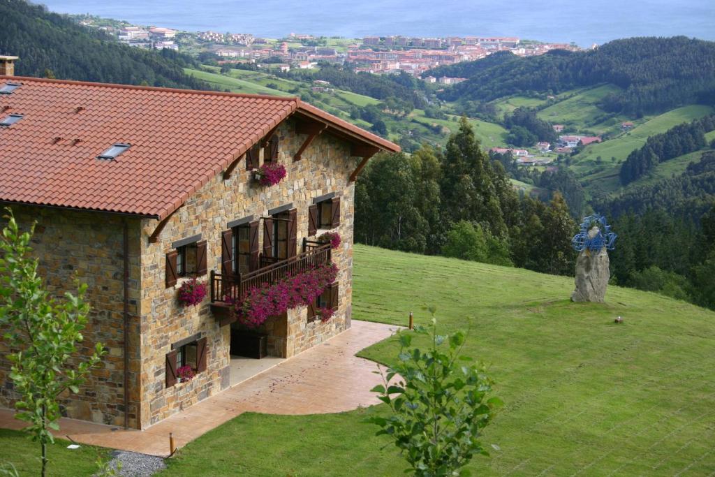 um edifício sobre uma colina com flores sobre ele em Eco Hotel Rural Lurdeia - Adults Only em Bermeo