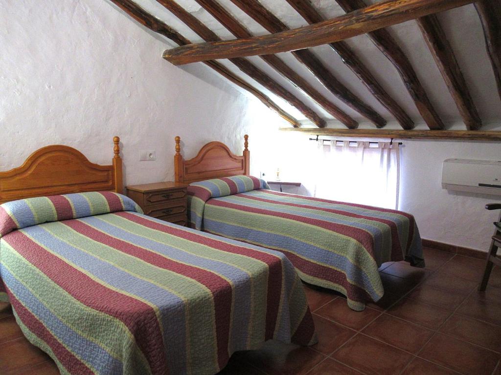 een slaapkamer met twee bedden met gestreepte lakens erop bij Casa Rural Dolores in Cuevas del Becerro