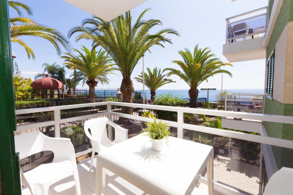 een balkon met een witte tafel en stoelen en palmbomen bij Apartamento Jumilla Vista Mar 23 in Playa del Inglés
