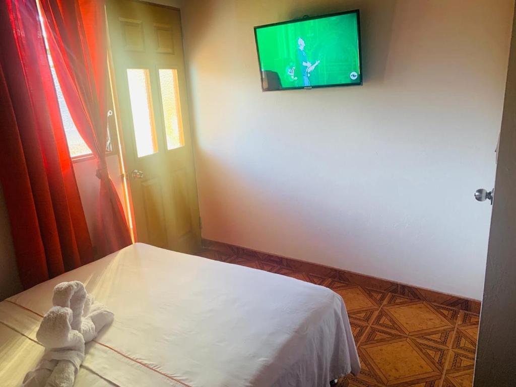 a teddy bear sitting on a bed in a room at Hospedaje 3 Esquinas in Guatapé