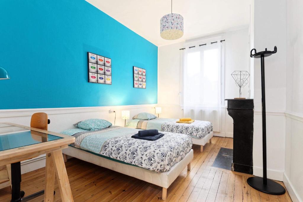 - 2 lits dans une chambre avec un mur bleu dans l'établissement L’atelier de Loane, au Havre