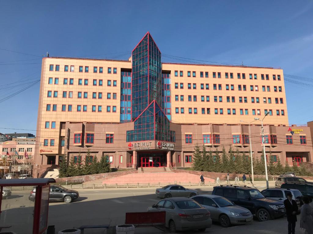 ヤクーツクにあるAZIMUT Hotel Yakutskの駐車場車を停めた大きな建物