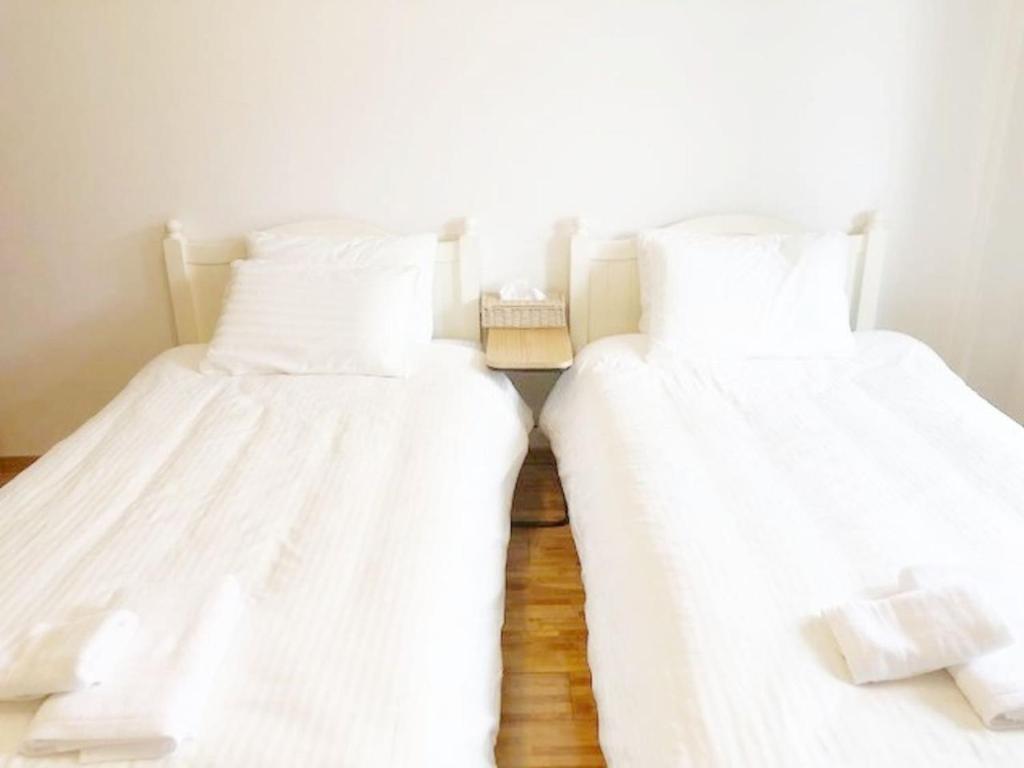 two beds in a room with white sheets at ラ・フィットヤマト103 in Fukuoka