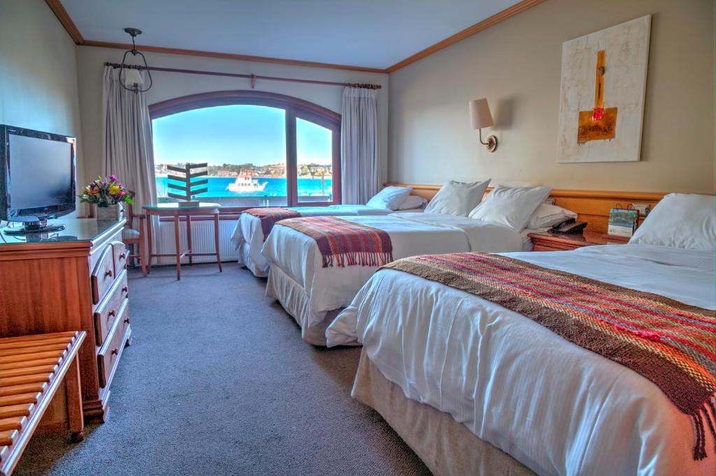 um quarto de hotel com duas camas e uma televisão em Hotel Cabaña Del Lago Puerto Varas em Puerto Varas