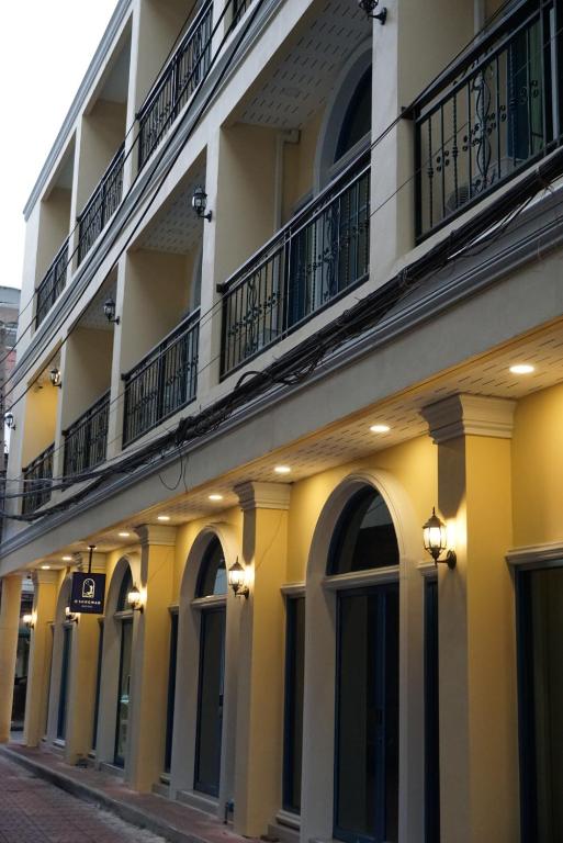 a yellow and white building with windows and balconies at Mangkon Hostel in Bangkok