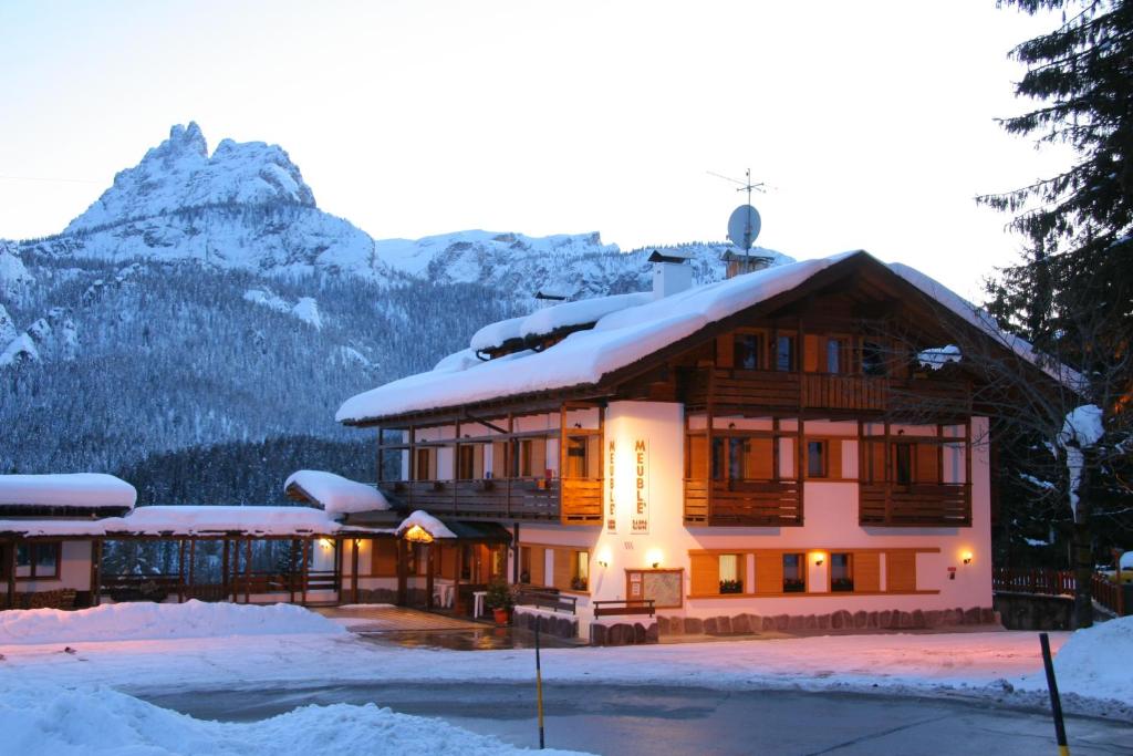 a large building with snow on top of it at Hotel Piccolo Pocol in Cortina dʼAmpezzo