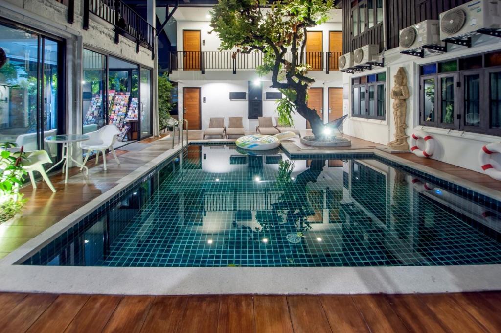 an indoor pool with a table and chairs in a house at Sathu Hotel in Chiang Mai