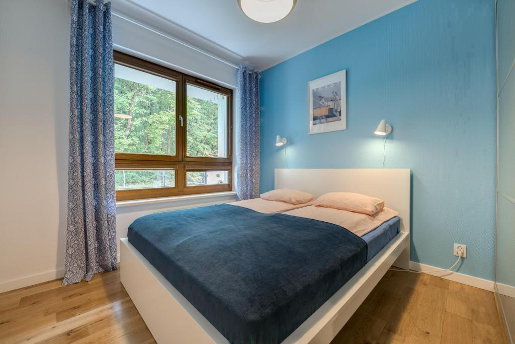 Un dormitorio con una cama con paredes azules y una ventana en Aquarius & FREE PARKING en Sopot