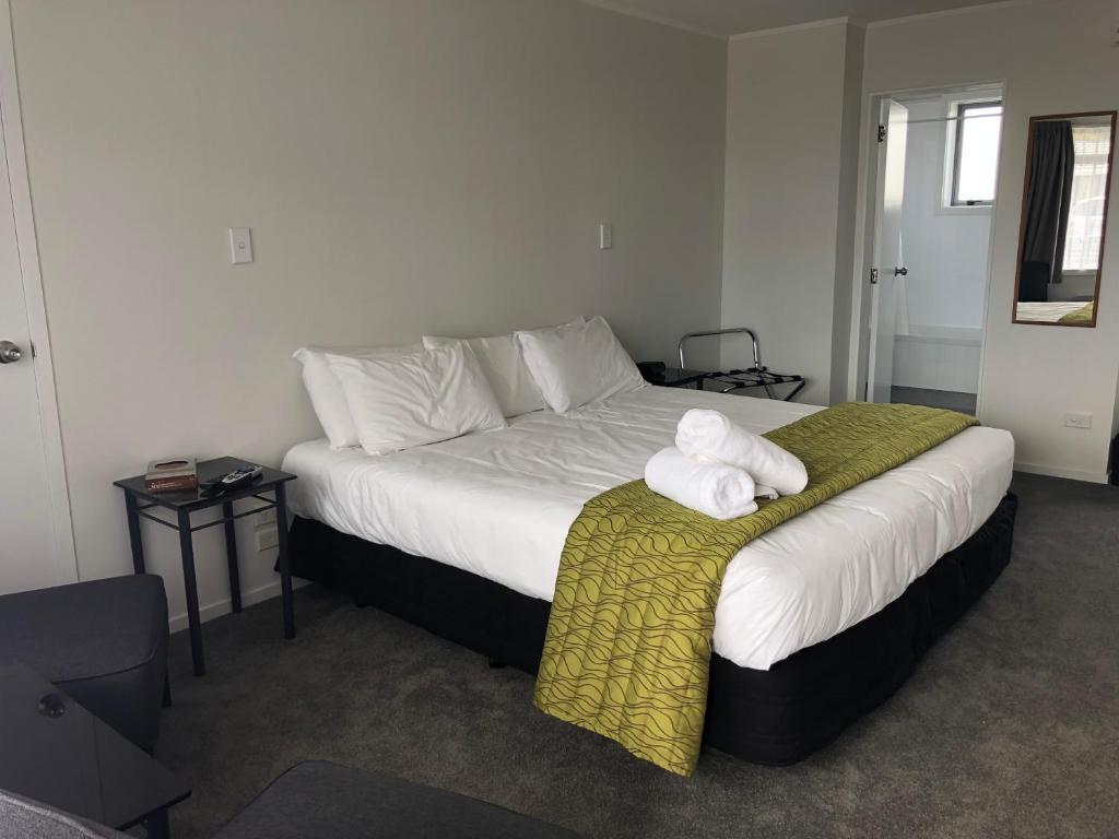 a bedroom with a large bed with towels on it at Ambassador Motor Inn in Tauranga