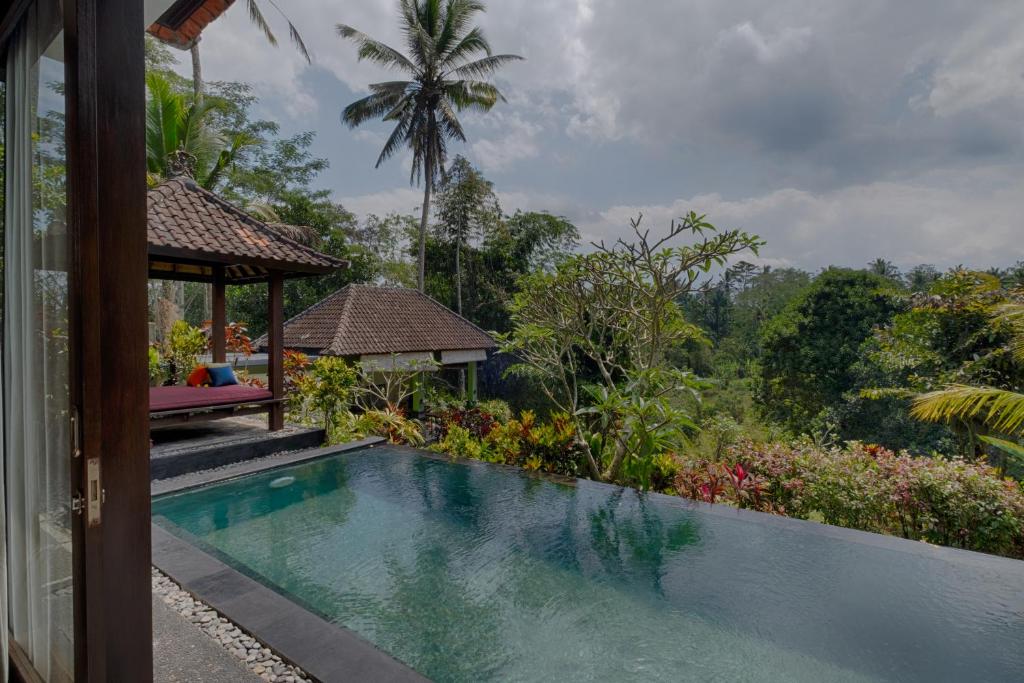 een zwembad met een prieel naast een huis bij Kaja Villa in Ubud