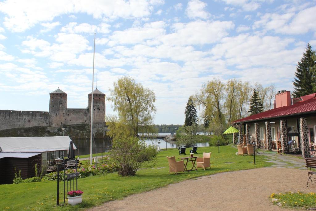 a building next to a lake and a castle at Lossiranta Lodge in Savonlinna