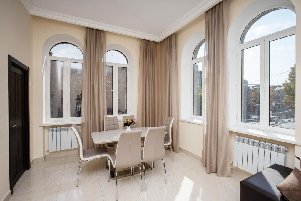 a dining room with windows and a table and chairs at Stay Inn Apartments at Mashtots Avenue 5A in Yerevan