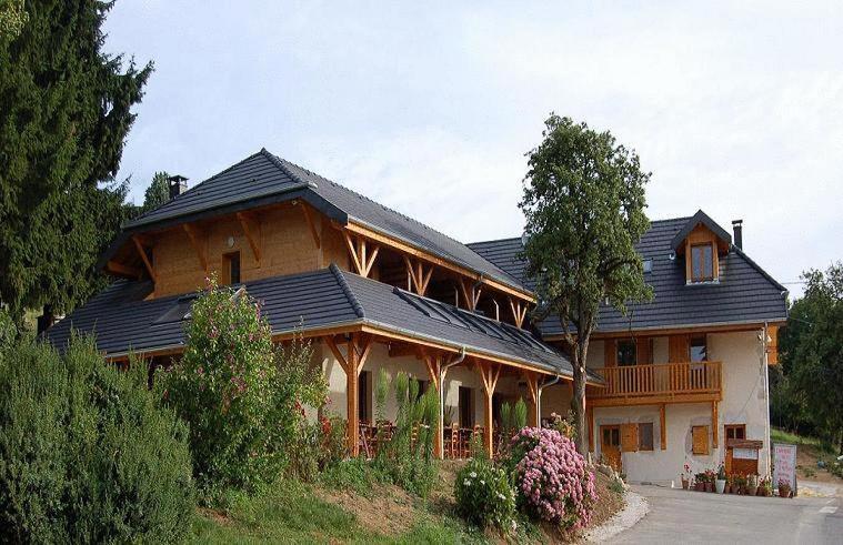 una gran casa de madera con techo negro en Auberge La Ferme De Ferrières en Pringy