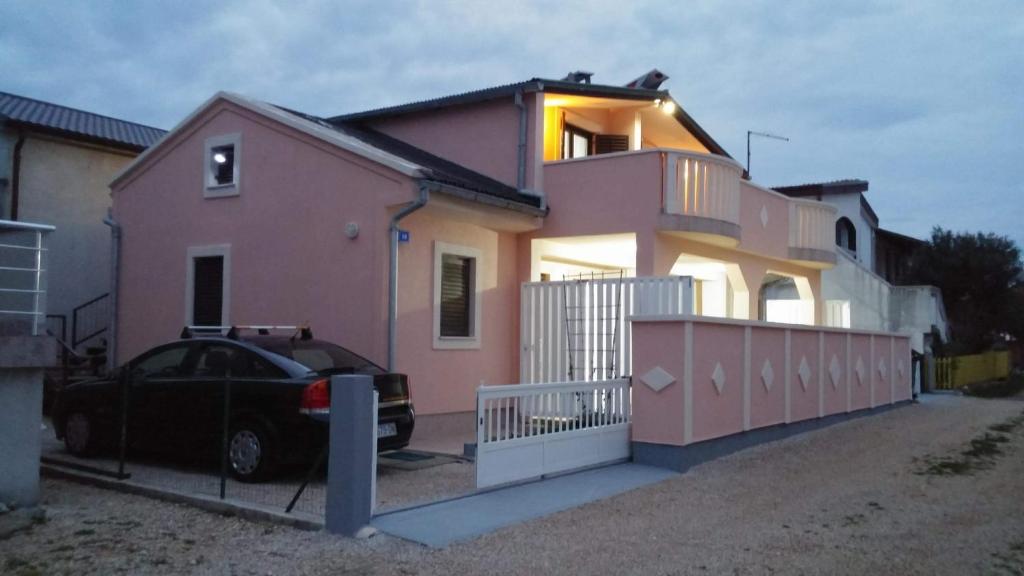 een roze huis met een auto ervoor geparkeerd bij Gizmo in Vir