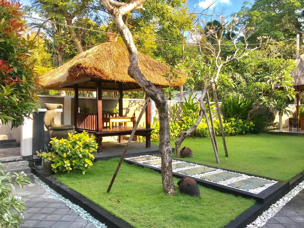 einen Garten mit einer Hütte mit zwei auf dem Gras liegenden Tieren in der Unterkunft The Celuk Homestay in Jimbaran