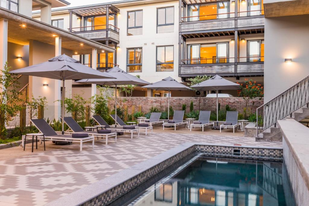 - une piscine avec des chaises et des parasols à côté d'un bâtiment dans l'établissement aha The Rex Hotel, à Knysna