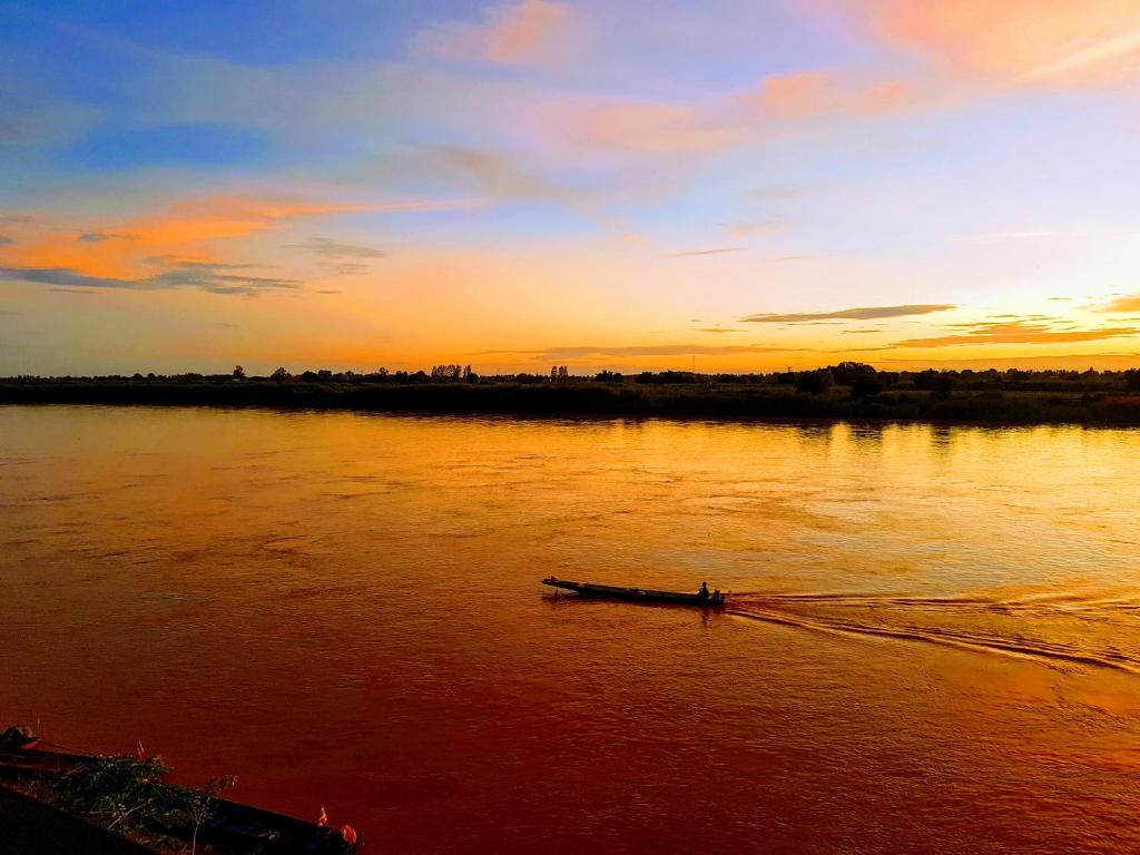 a boat on a river at sunset at นกฮูกเฮ้าส์ บ้านพักริมโขง in Nong Khai