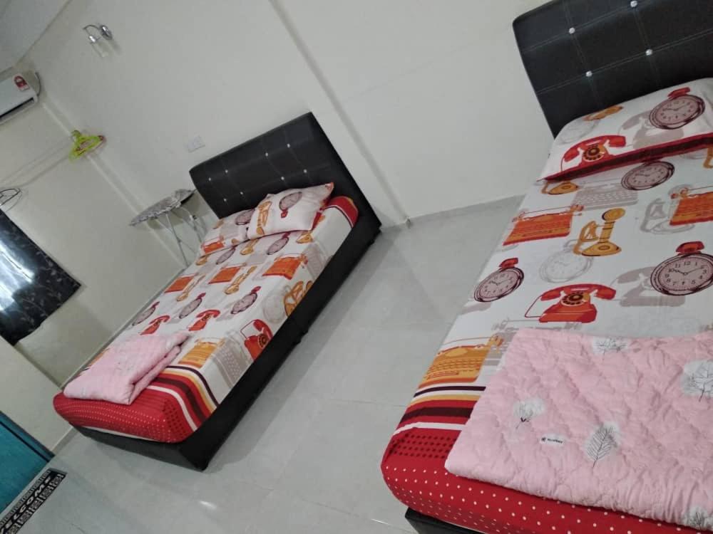 a bedroom with two beds and a red bedskirts at Niyaz Inn in Pantai Cenang