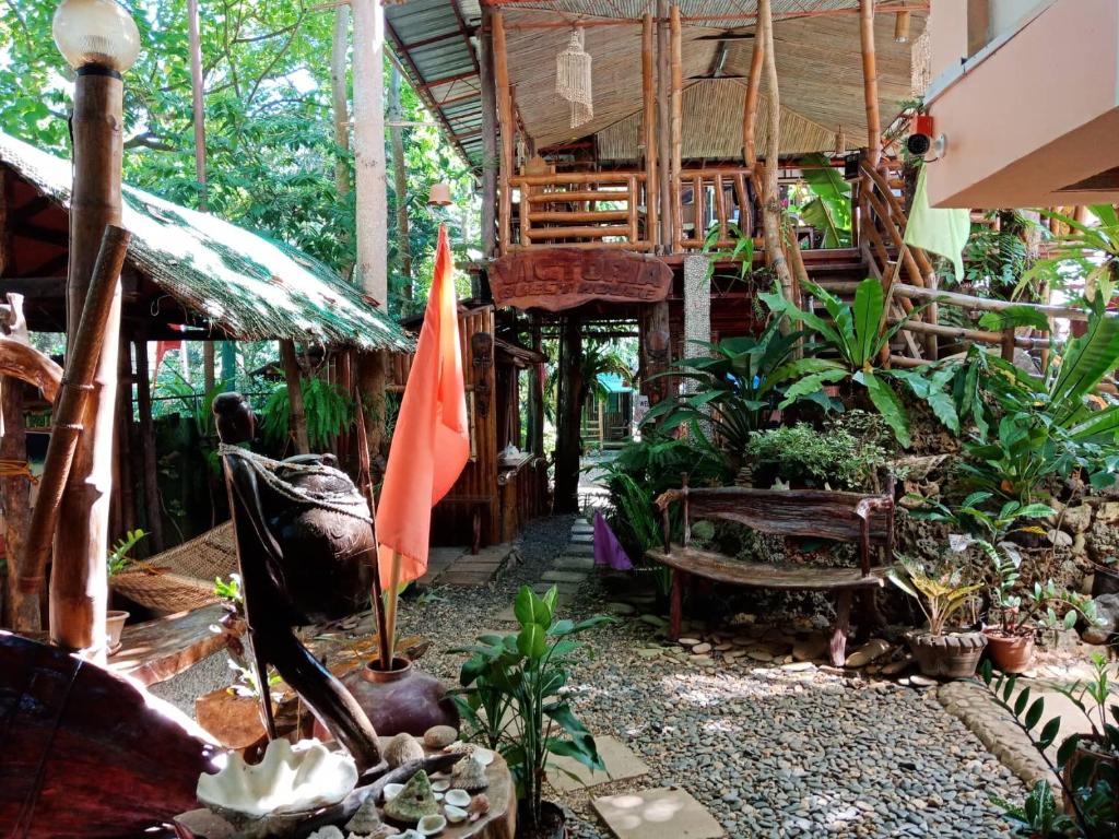un jardín con sombrilla, banco y árboles en Victoria Guest House and Cottages, en Puerto Princesa City