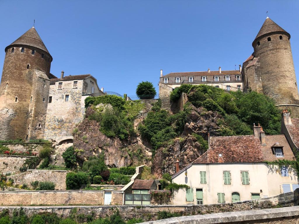 ein Schloss auf einem Hügel mit Häusern in der Unterkunft Bâtisse du pont pinard et son granit rose in Semur-en-Auxois