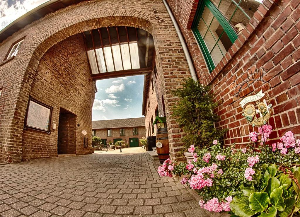 einen Eingang zu einem Backsteingebäude mit rosa Blumen in der Unterkunft Landhaus Göddertzhof in Erkelenz