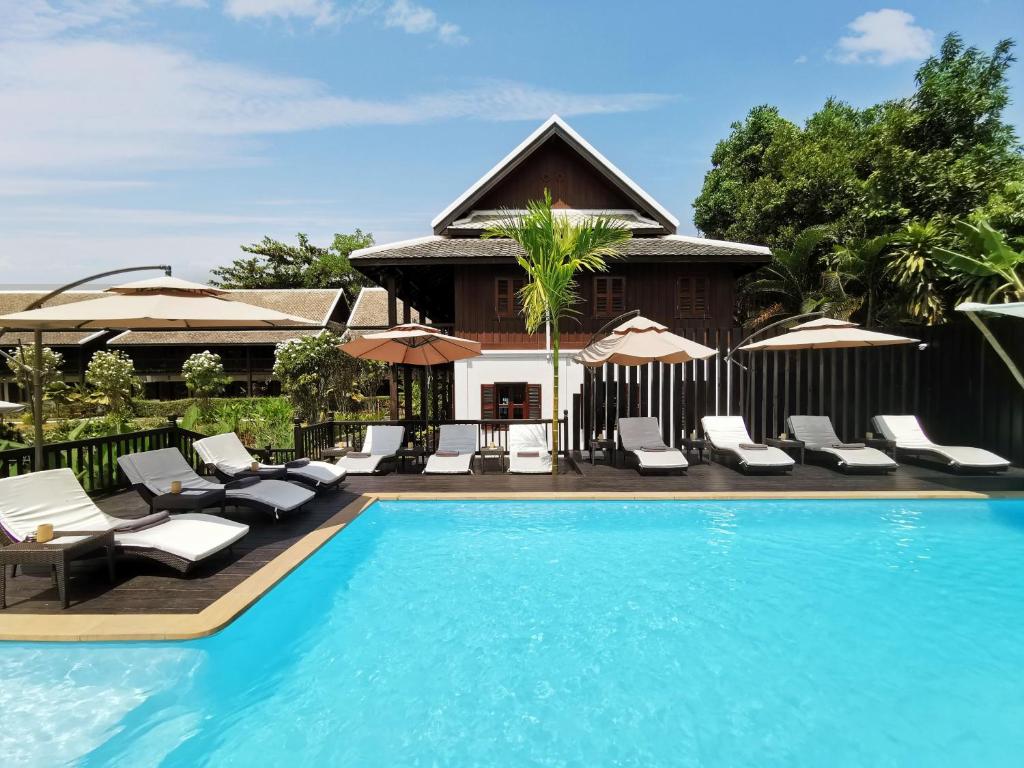 a swimming pool with lounge chairs and a house at Sanctuary Hotel Luang Prabang in Luang Prabang