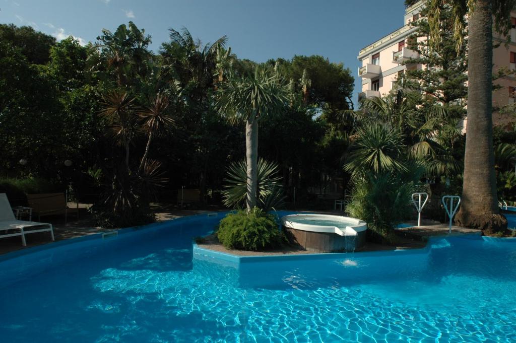 uma piscina com banheira e palmeiras em Reginna Palace Hotel em Maiori