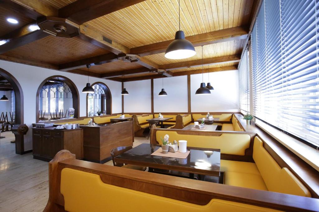 a restaurant with yellow seats and tables and windows at F Hotel in Hörsching
