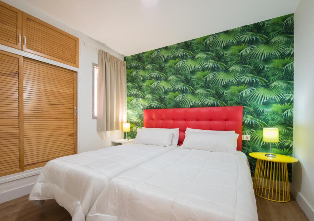 a bedroom with a large white bed with a red headboard at Bungalows Artemisa Gay Men Only in Playa del Ingles